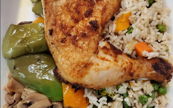 Roasted chicken on a bed of rice with peppers and mushrooms